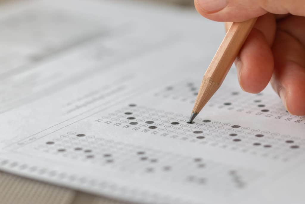 ASVAB Test Preparation Tips Student hand testing doing test exam with pencil drawing selected choices on answer sheet in school final exams at college or university. Taking multiple choice for assessment in examination classroom